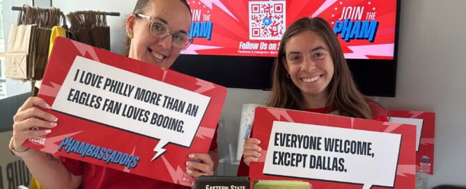 Two women holding Eagles Cheer Cards in Love Park