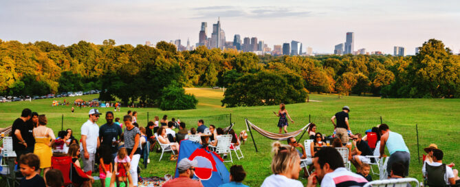 A group of people sitting on the Belmont Plateau overlooking Center City Philadelphia