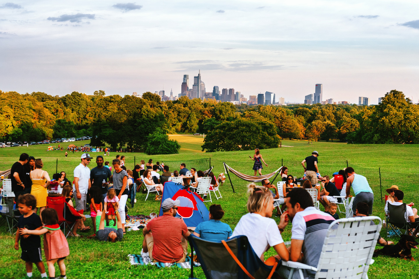 A group of people sitting on the Belmont Plateau overlooking Center City Philadelphia