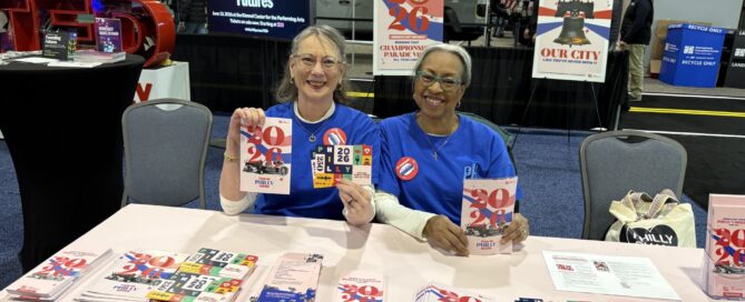 A white and black female sitting behind a table promoting the events of 2026 at the Philadelphia Auto Show.