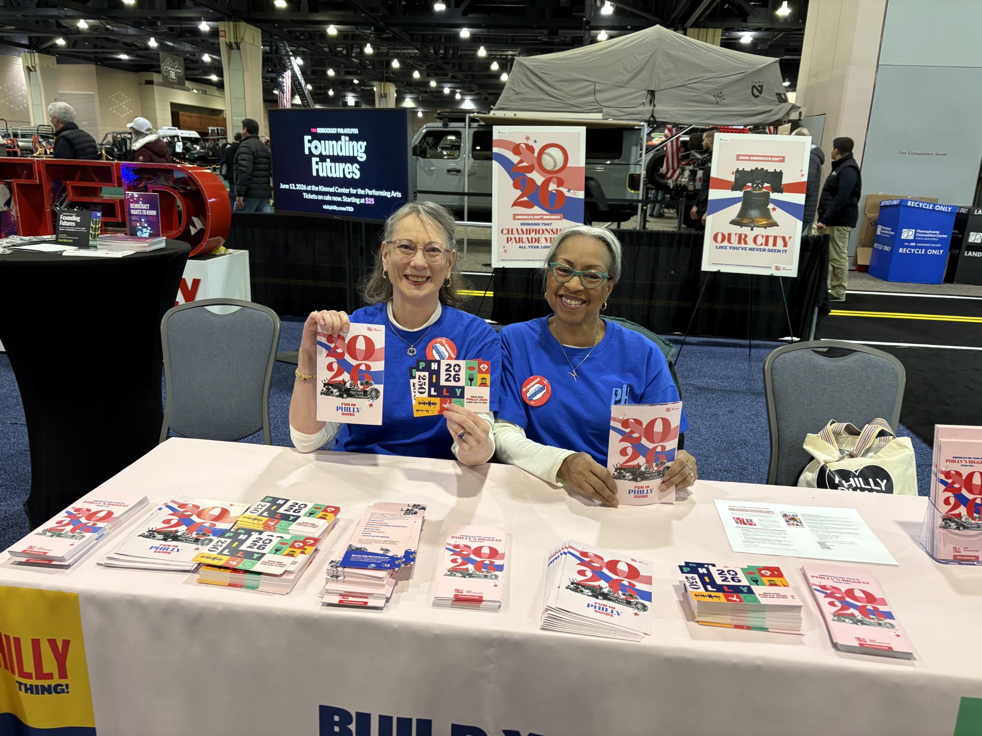 A white and black female sitting behind a table promoting the events of 2026 at the Philadelphia Auto Show.